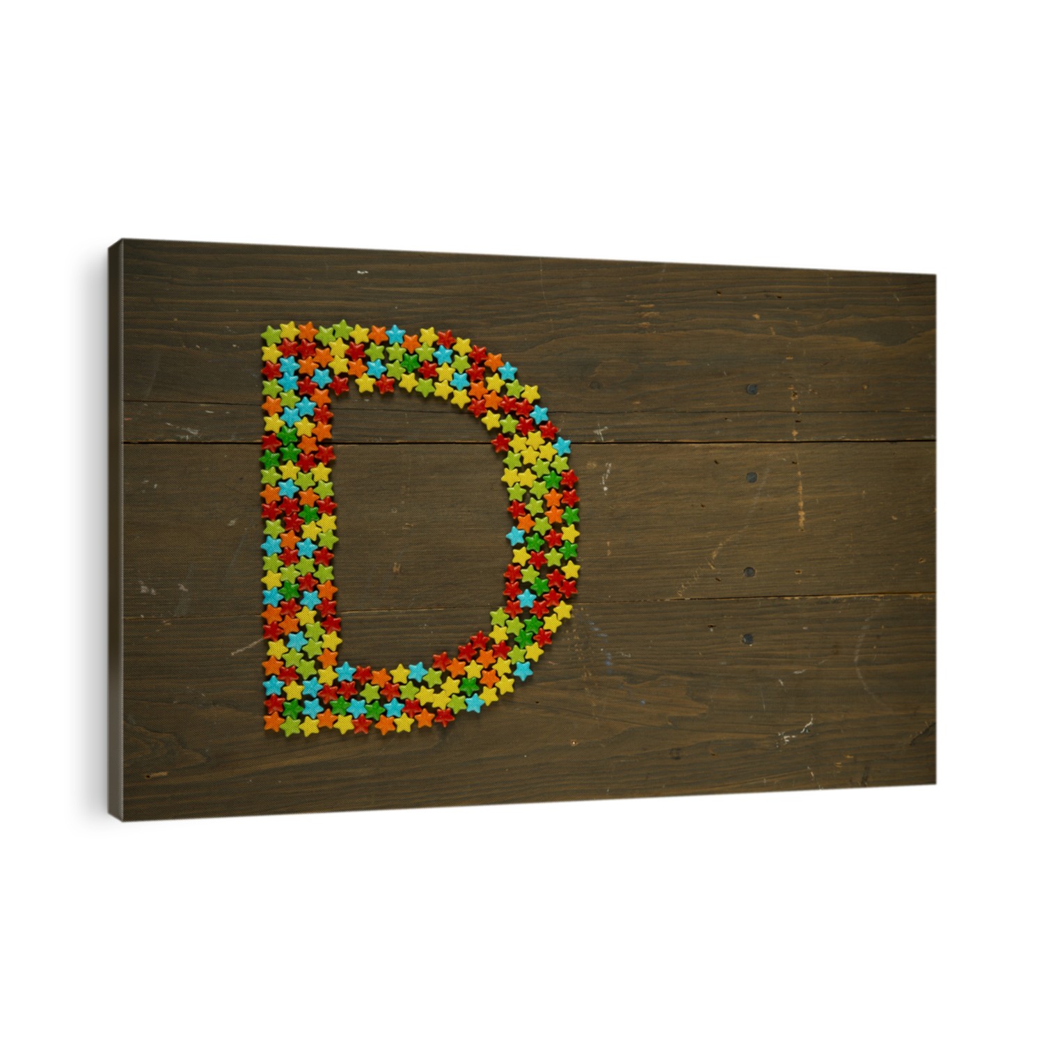 Letter D from alphabet made with star shape candy on a wooden background