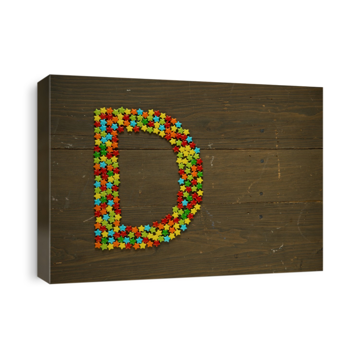 Letter D from alphabet made with star shape candy on a wooden background